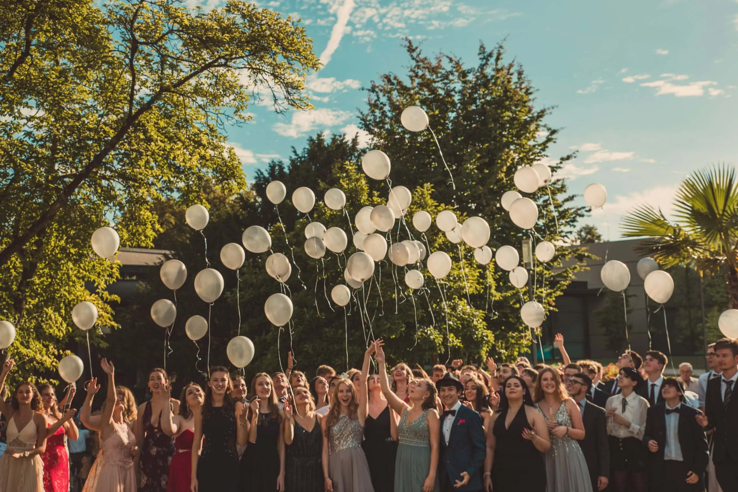 Abiturjahrgang mit weißen Luftballons beim Gruppenfoto