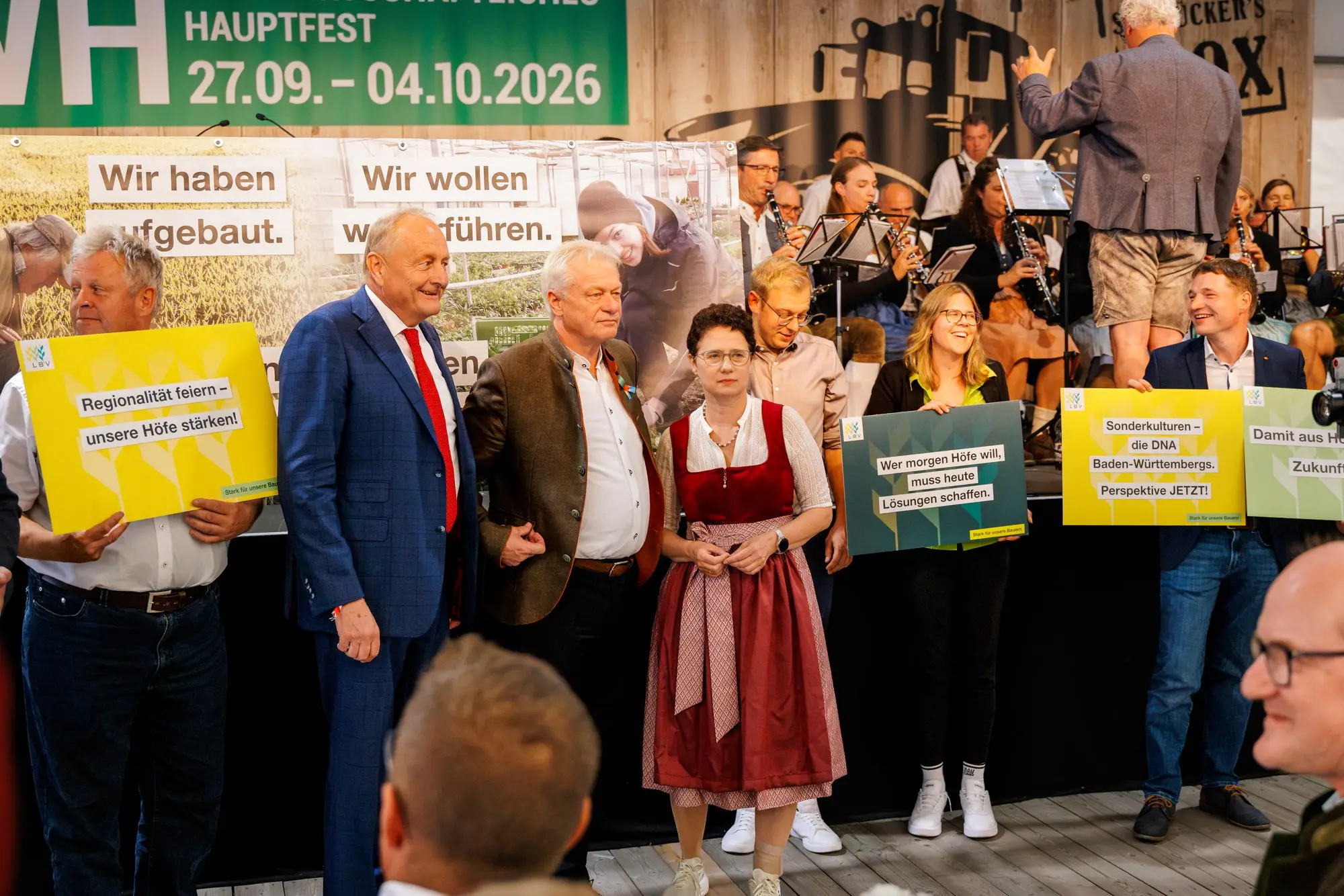 Gruppe mit Schildern auf der Bühne des Bauerntags vor der LWH-Rückwand