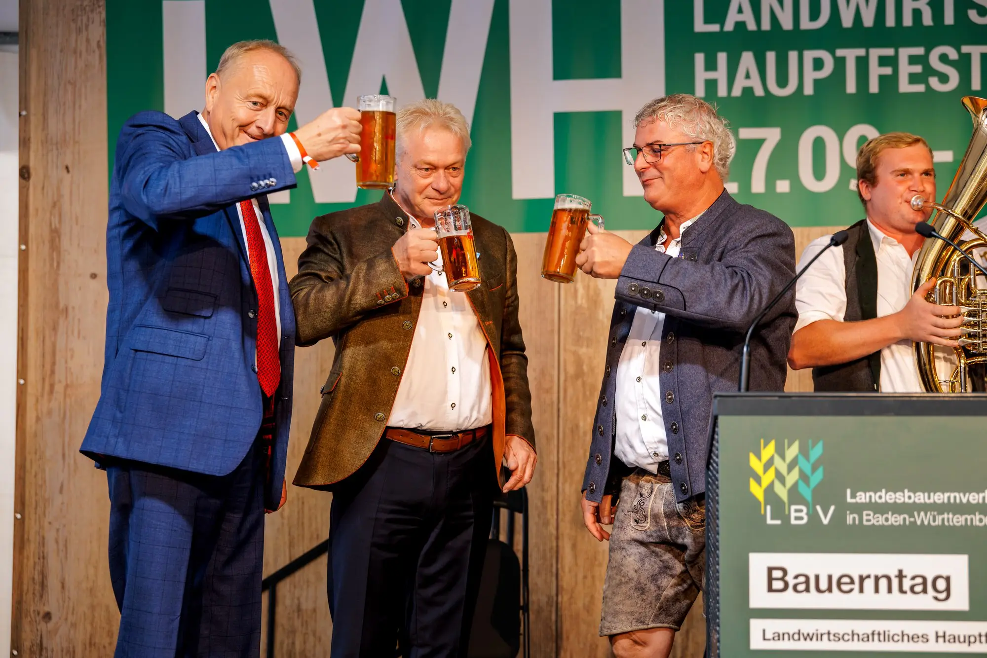 Anstoßen auf der Bühne: Joachim Rukwied und Alois Rainer mit Maßkrügen, daneben die Bauernkapelle
