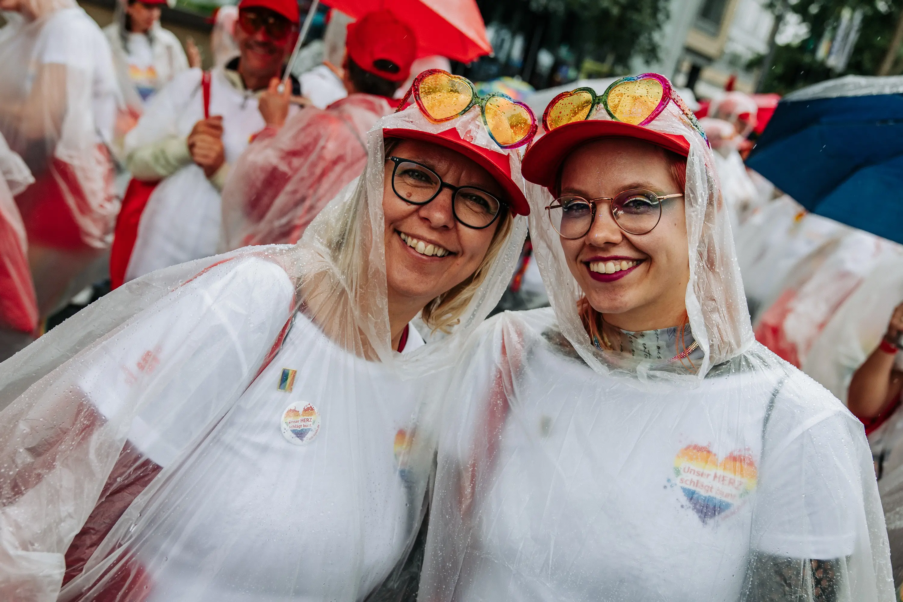 Zwei Teilnehmerinnen der Parade in Regenponchos, trotz Dauerregen bestens gelaunt