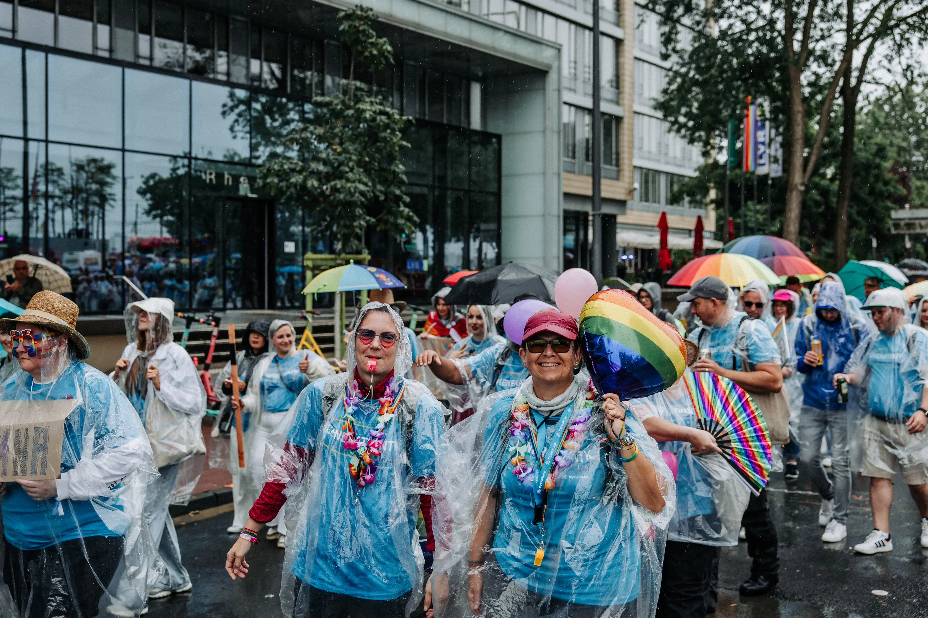Regenbogenfahnen und Regenschirme im Zug der Cologne Pride 2025