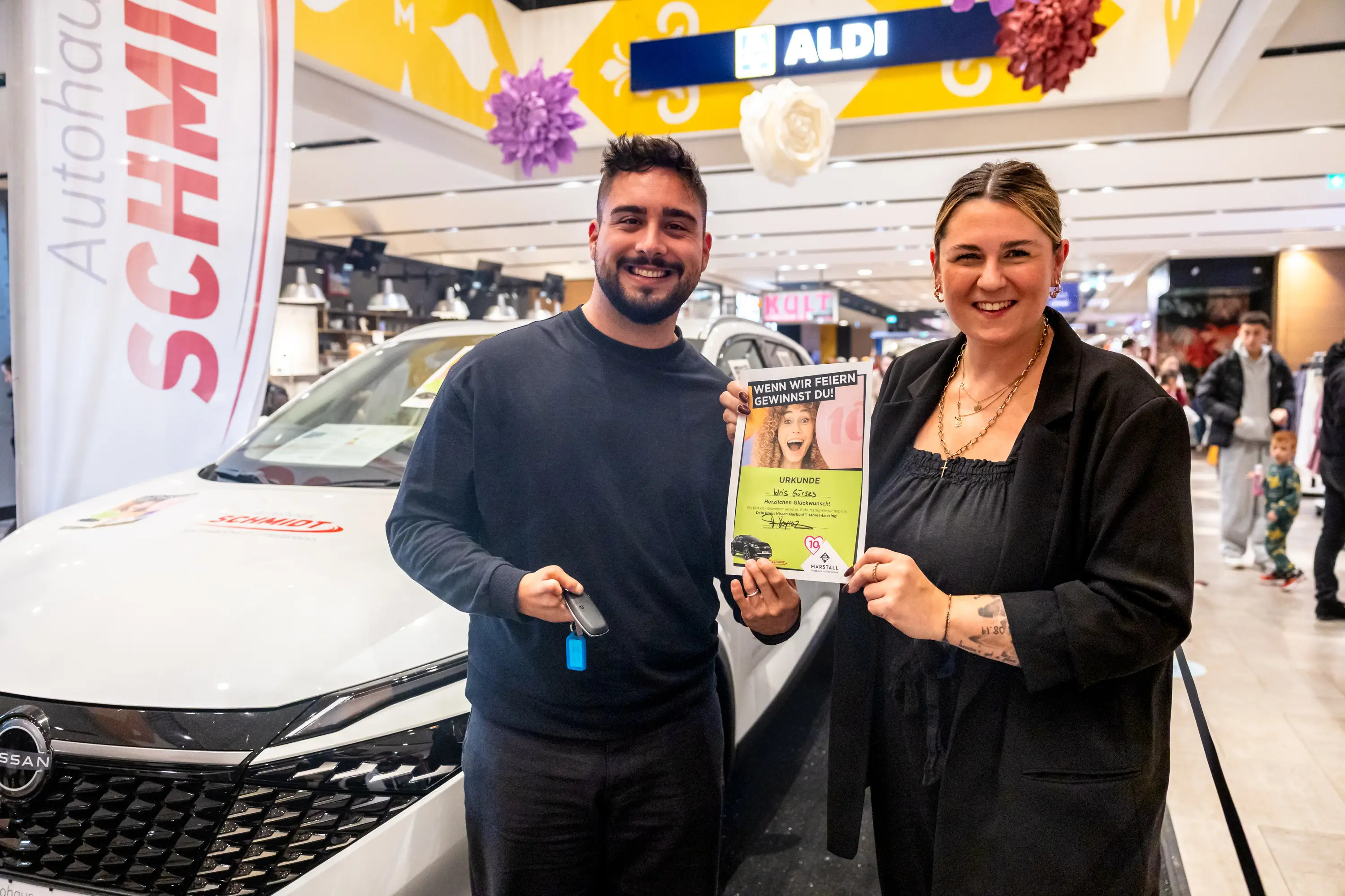 Übergabe des Hauptgewinns vor dem Fahrzeug des Partnerautohauses