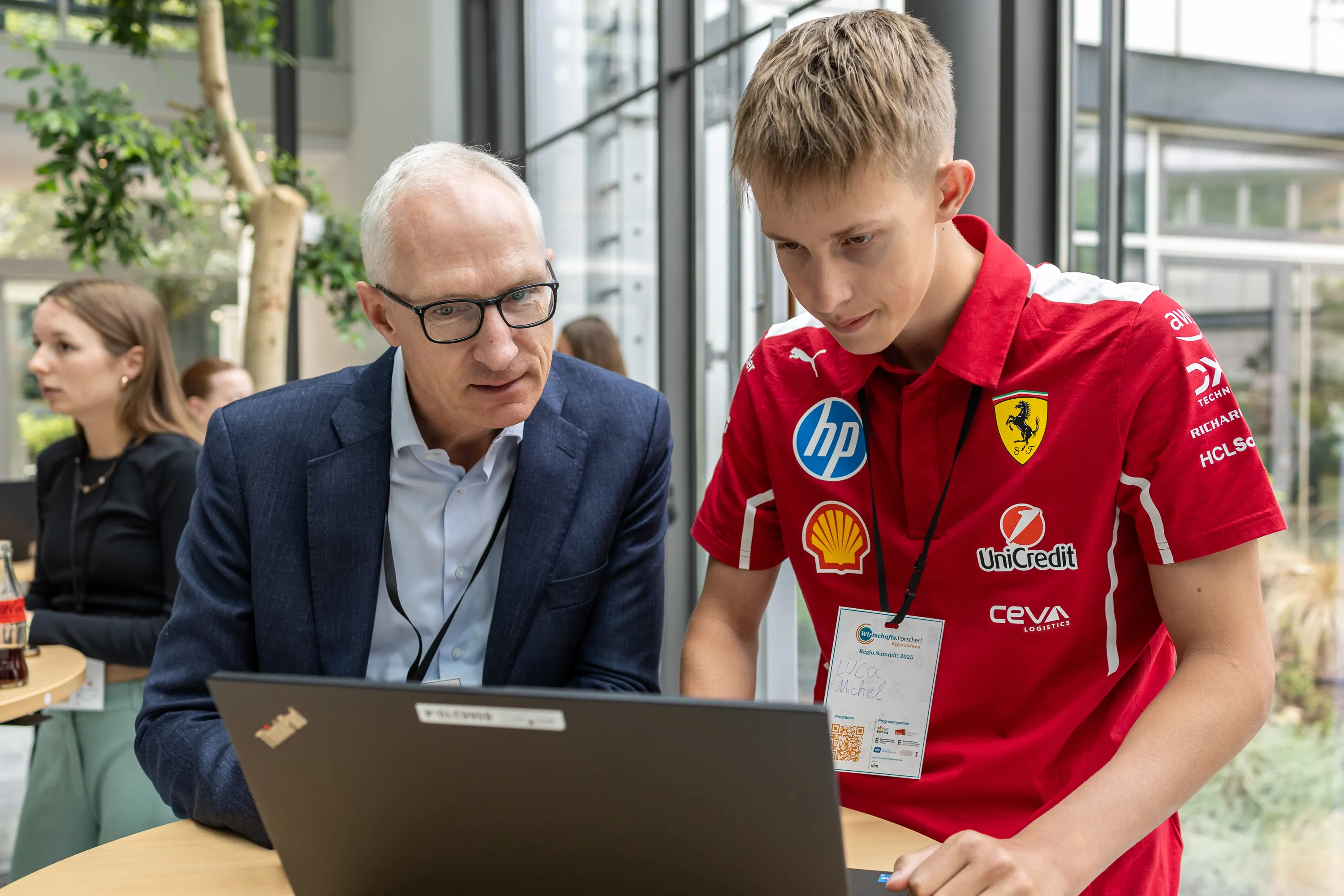 Ein Gast aus der Wirtschaft und ein Schüler besprechen gemeinsam ein Forschungsprojekt am Laptop