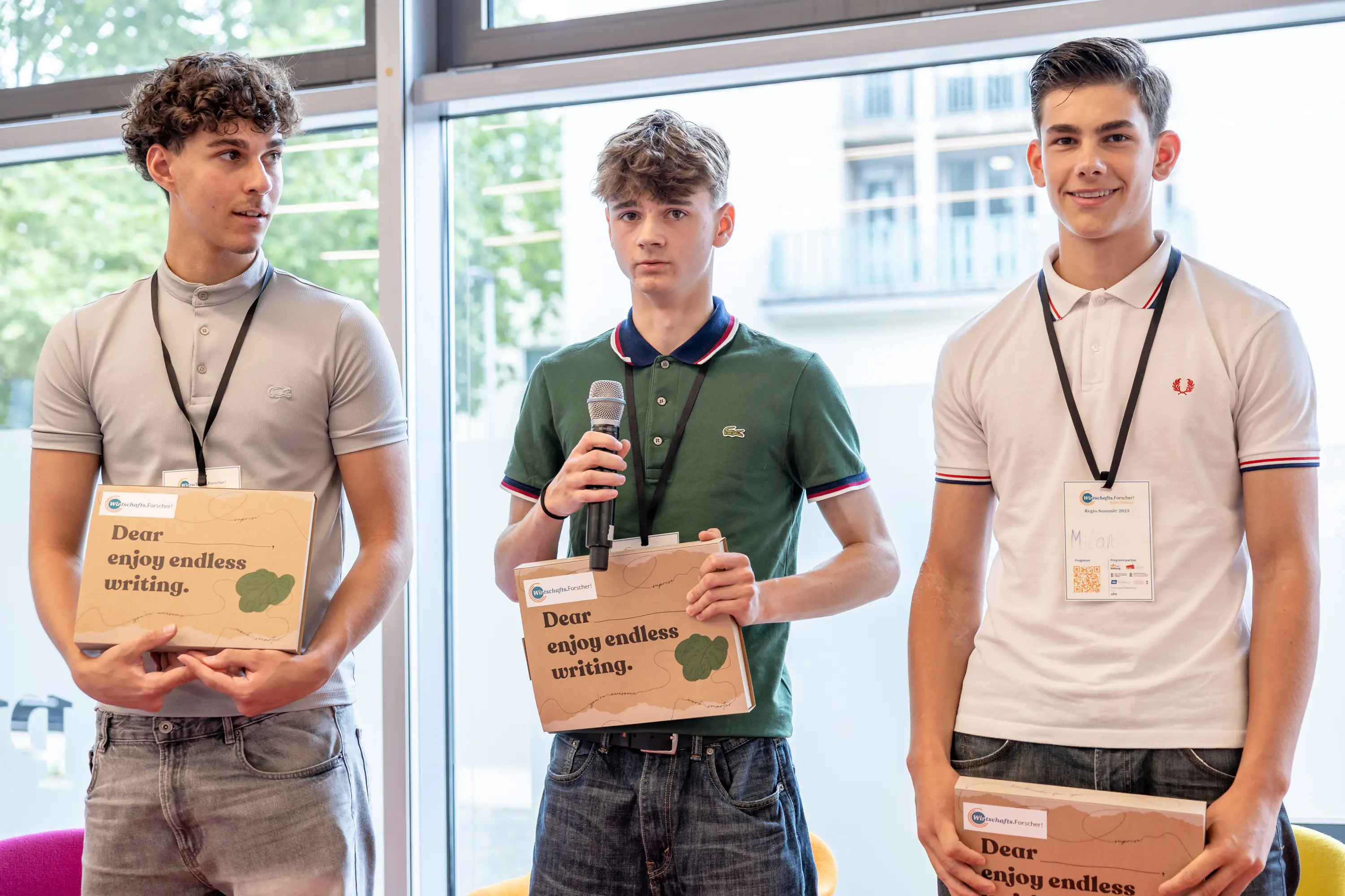 Drei Schüler mit ihren Auszeichnungen auf der Bühne